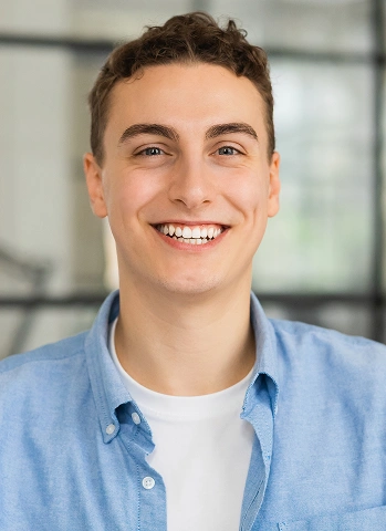 Young man with short hair smiling confidently in a bright dental office setting