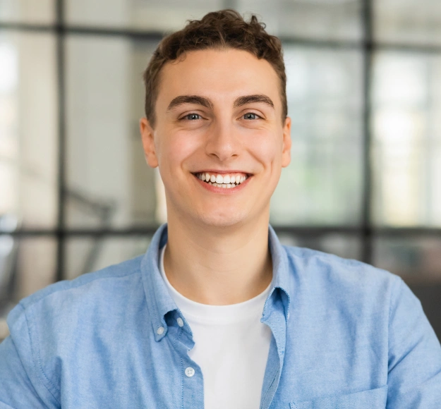 Young man with short hair smiling confidently in a bright dental office setting
