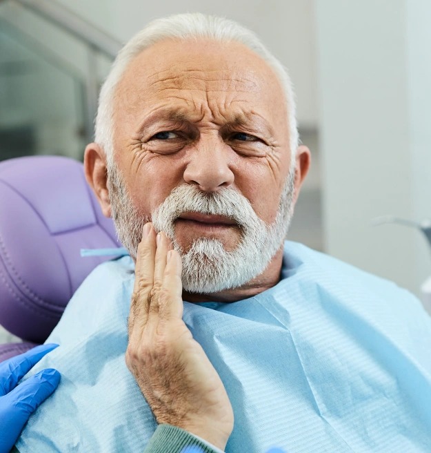 Older man with a white beard sitting in a dental chair during a tooth extraction consultation